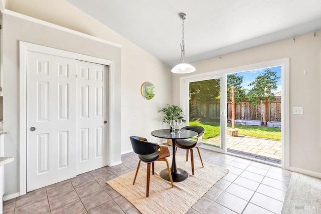 dining space with light tile patterned floors, baseboards, and lofted ceiling