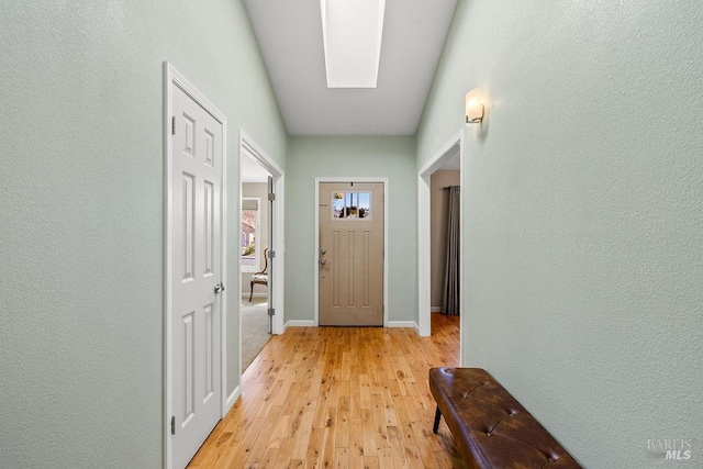 doorway with light wood finished floors and baseboards