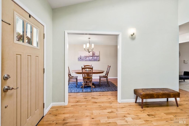 entrance foyer featuring light wood finished floors, baseboards, and an inviting chandelier