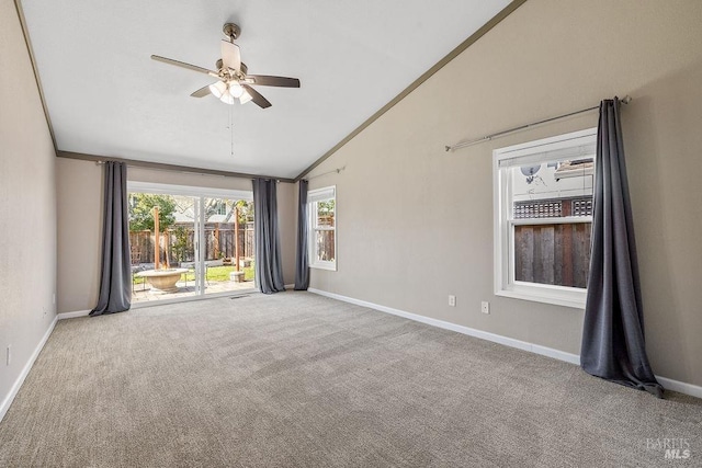 carpeted spare room with vaulted ceiling, a ceiling fan, baseboards, and ornamental molding