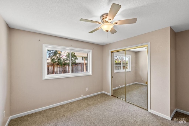 unfurnished bedroom with carpet flooring, baseboards, a closet, and a textured ceiling