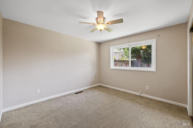 unfurnished room featuring carpet flooring, a ceiling fan, visible vents, and baseboards