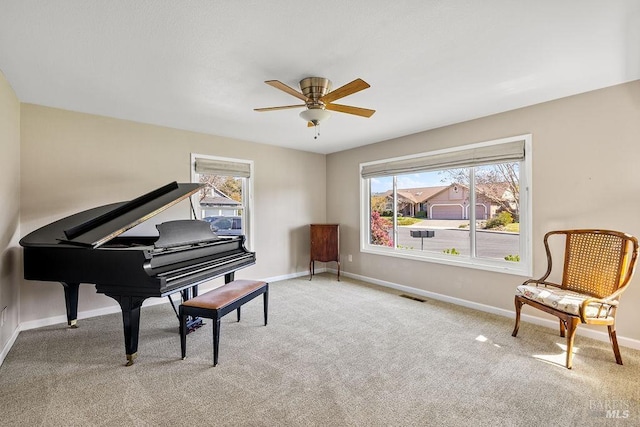 living area with a wealth of natural light, visible vents, a ceiling fan, and baseboards