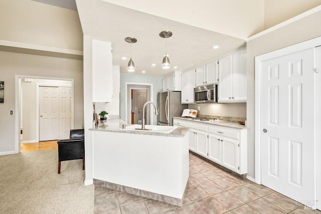 kitchen with white cabinets, appliances with stainless steel finishes, a peninsula, and a sink