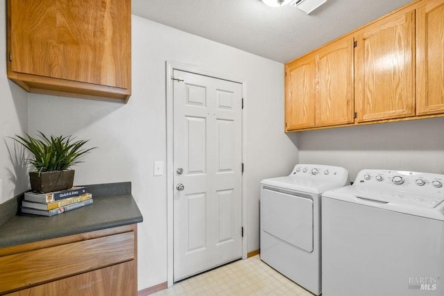 laundry area featuring washer and dryer, cabinet space, light floors, and a textured ceiling