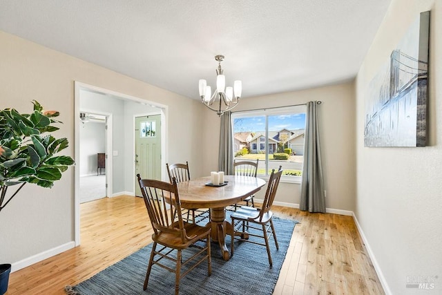 dining space featuring light wood-type flooring, baseboards, and an inviting chandelier