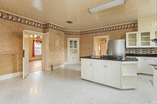 kitchen featuring dark countertops, a chandelier, appliances with stainless steel finishes, white cabinets, and a sink