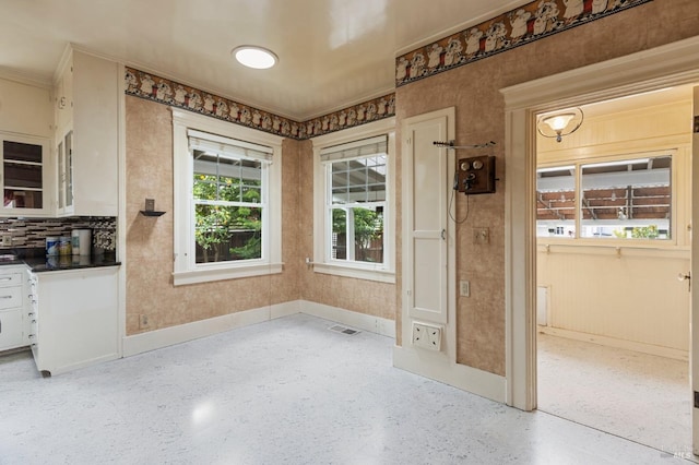 interior space with dark countertops, visible vents, tasteful backsplash, baseboards, and white cabinets