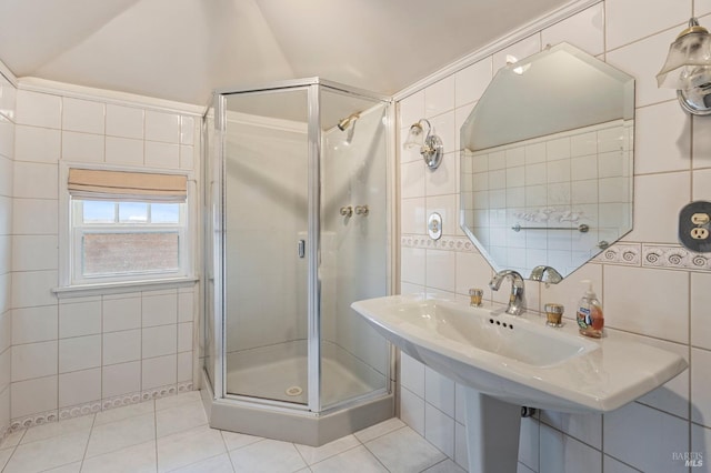 full bath featuring tile walls, tile patterned floors, a shower stall, and a sink