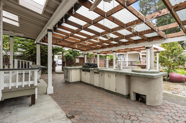 view of patio with area for grilling and a pergola