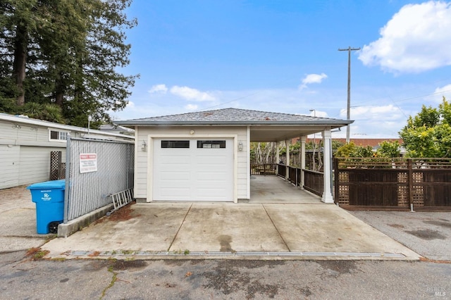 garage featuring a detached garage, concrete driveway, and fence