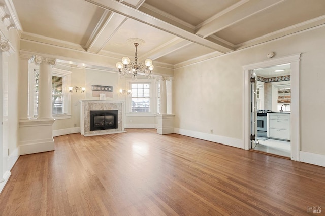 unfurnished living room with beamed ceiling, a notable chandelier, ornamental molding, coffered ceiling, and wood finished floors