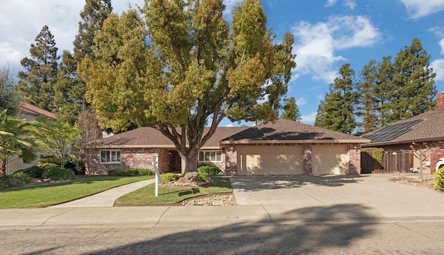 ranch-style house featuring driveway, a front lawn, fence, an attached garage, and brick siding