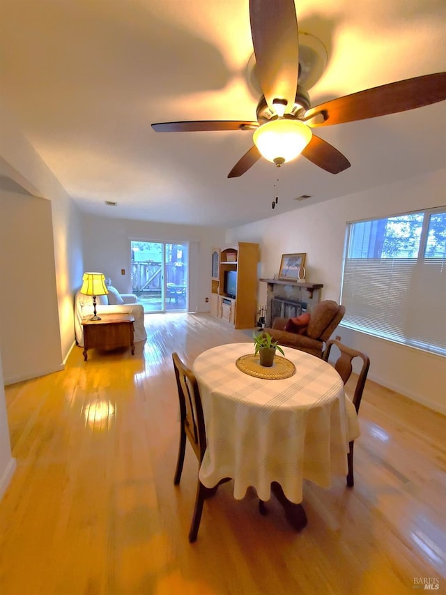 dining area with light wood finished floors, visible vents, and a ceiling fan