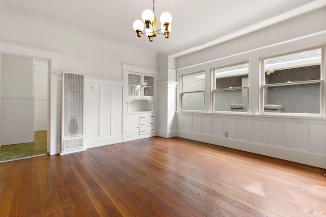 unfurnished dining area featuring an inviting chandelier and hardwood / wood-style floors