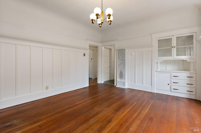 unfurnished bedroom with a notable chandelier, dark wood-style flooring, and two closets