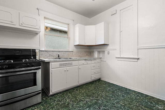 kitchen with a sink, white cabinetry, dark floors, light countertops, and gas range