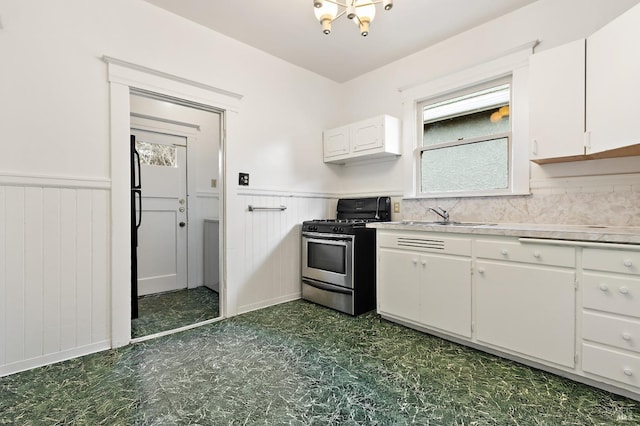 kitchen featuring light countertops, dark floors, stainless steel gas stove, and wainscoting