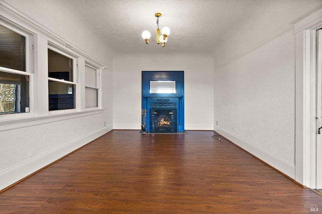 entryway featuring a fireplace with flush hearth, a textured ceiling, wood finished floors, an inviting chandelier, and baseboards