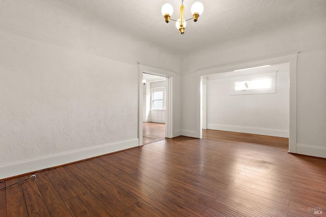 unfurnished room featuring a wealth of natural light, an inviting chandelier, and hardwood / wood-style floors