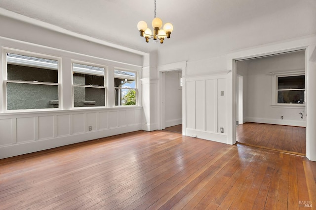 empty room with wood-type flooring and a chandelier