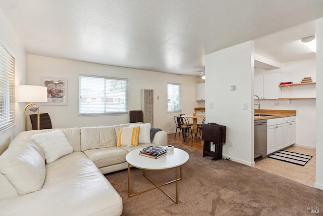 living room featuring light colored carpet, a ceiling fan, and baseboards