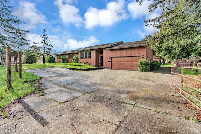 ranch-style home with board and batten siding, fence, a front yard, a garage, and driveway