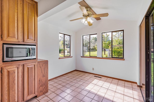 unfurnished dining area featuring light tile patterned floors, visible vents, baseboards, and vaulted ceiling