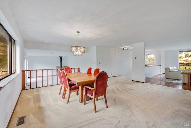 dining area featuring visible vents, light colored carpet, and a chandelier