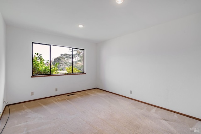 unfurnished room featuring baseboards, visible vents, and light carpet