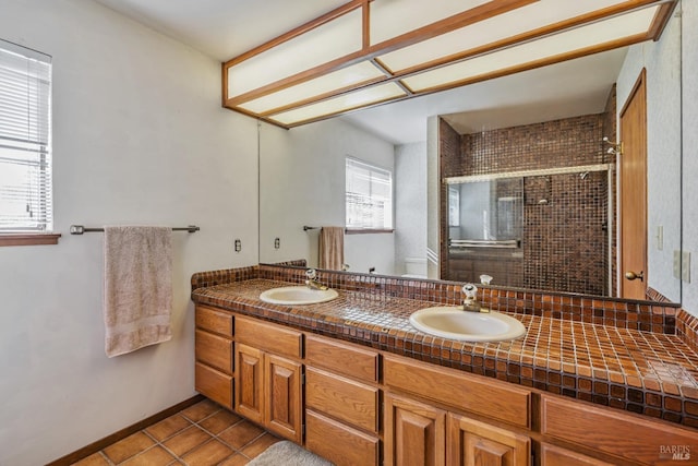 full bath with a shower stall, double vanity, tile patterned floors, and a sink