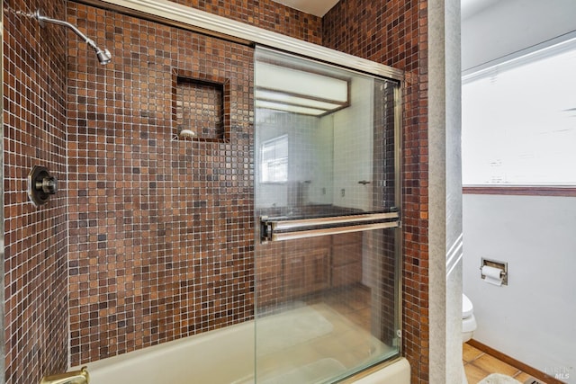 bathroom featuring combined bath / shower with glass door and toilet