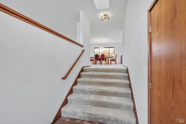 stairs featuring baseboards, a skylight, and an inviting chandelier