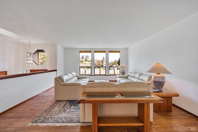 living room with a notable chandelier, wood finished floors, and baseboards