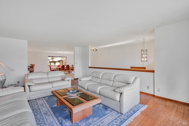 living area with an inviting chandelier, baseboards, and wood-type flooring