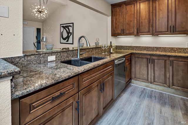 kitchen with dark stone counters, light wood-style flooring, lofted ceiling with beams, a sink, and dishwasher