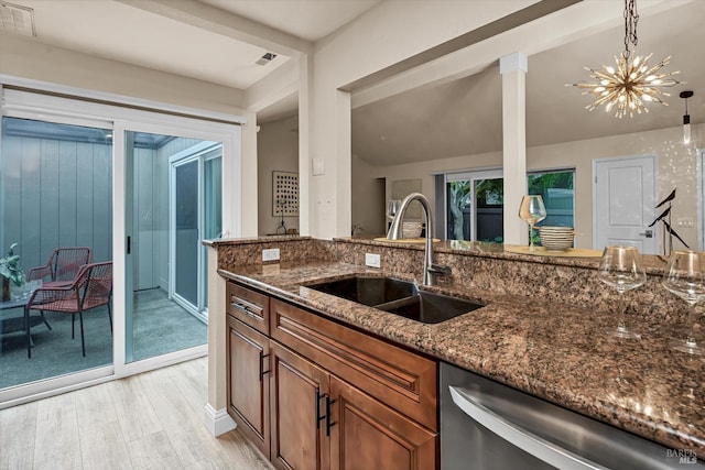 kitchen with dark stone countertops, brown cabinetry, visible vents, a sink, and dishwasher