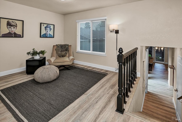 living area with an upstairs landing, baseboards, and wood finished floors