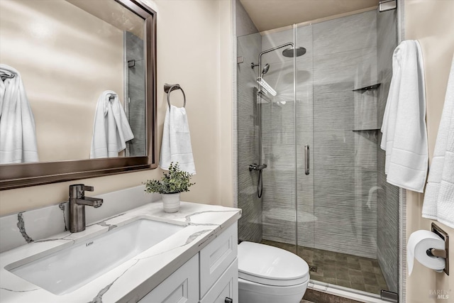 bathroom with a stall shower, toilet, and vanity