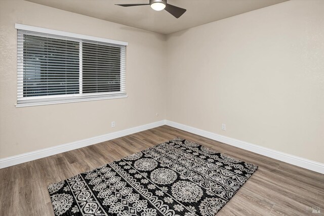 unfurnished room featuring baseboards, wood finished floors, and a ceiling fan