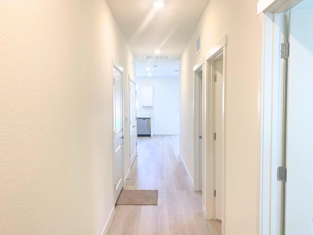 corridor featuring light wood-style floors, visible vents, and baseboards