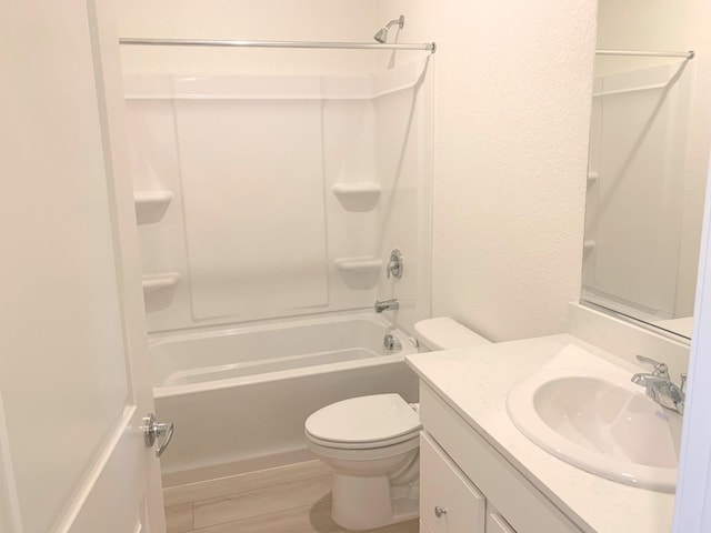 bathroom featuring vanity, toilet, tub / shower combination, and a textured wall