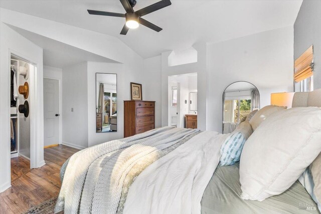 bedroom featuring ensuite bath, a ceiling fan, vaulted ceiling, baseboards, and wood finished floors