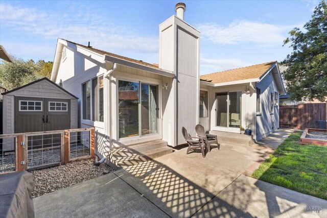 rear view of house with a patio, an outdoor structure, a storage unit, entry steps, and fence