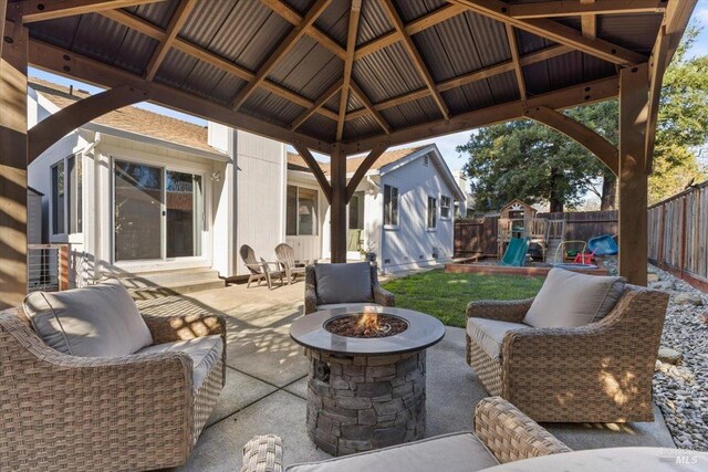 view of patio / terrace with entry steps, a playground, a gazebo, an outdoor fire pit, and a fenced backyard