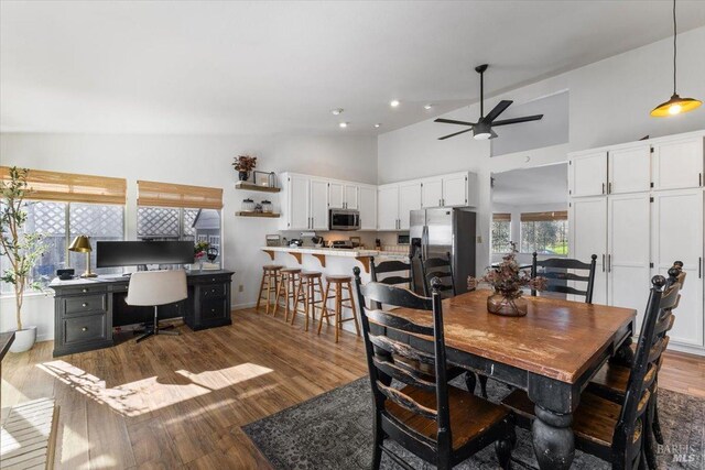 dining room featuring ceiling fan, high vaulted ceiling, wood finished floors, and baseboards