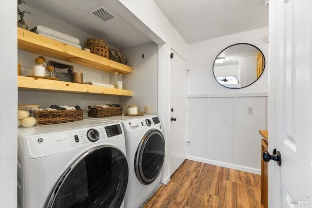 laundry area featuring wood finished floors, separate washer and dryer, laundry area, baseboards, and visible vents