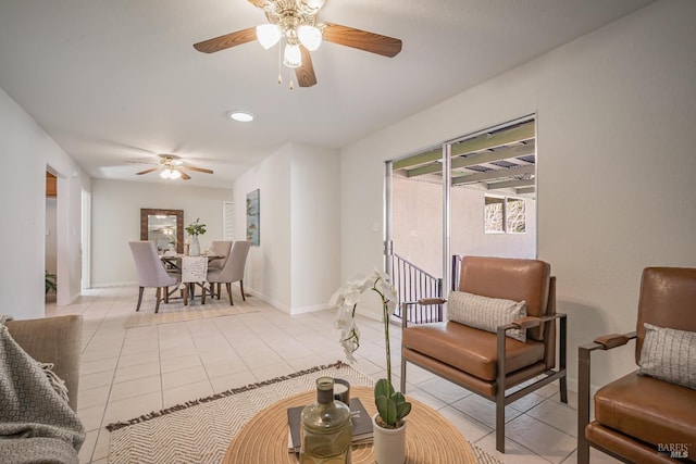 living area with light tile patterned floors, baseboards, and a ceiling fan