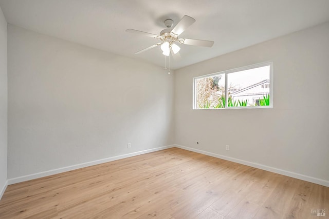 spare room featuring baseboards, light wood finished floors, and ceiling fan