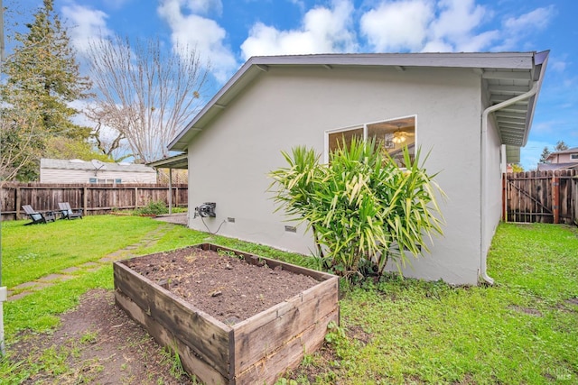 exterior space featuring a vegetable garden, a fenced backyard, stucco siding, crawl space, and a lawn